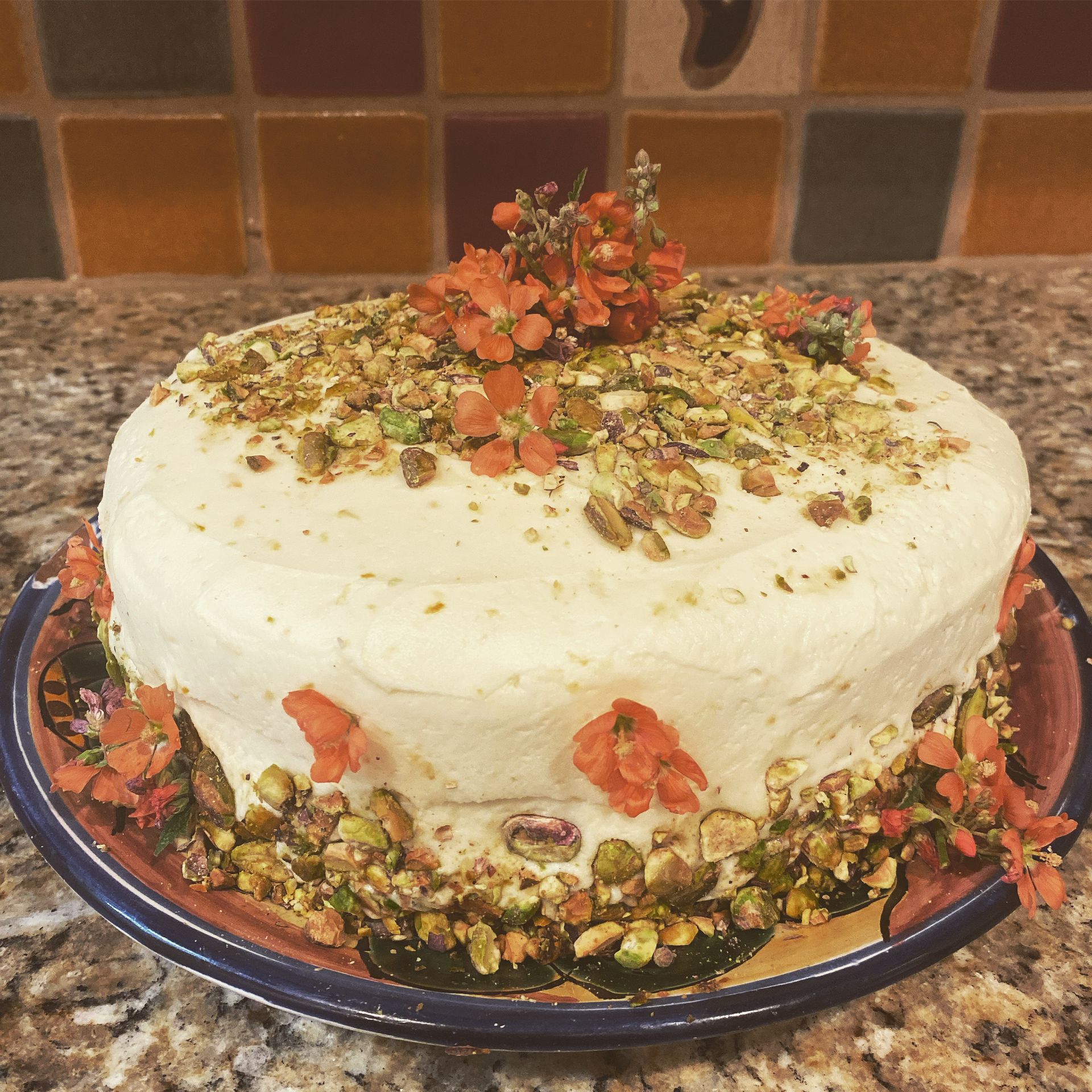 A cake with pistachios and flowers on top of it