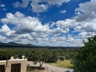 A view of a valley with mountains in the background and clouds in the sky.