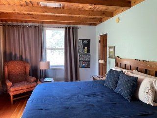 A bedroom with a large bed and a chair