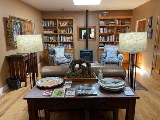A living room with a table , chairs , lamps and bookshelves.