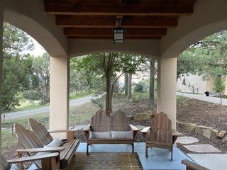 A patio with a couch and chairs under an archway