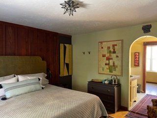 A bedroom with a large bed and a painting on the wall