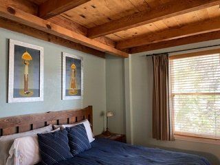 a bedroom with a bed , two pictures on the wall and a window .