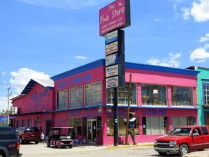 A red truck is parked in front of a pink store