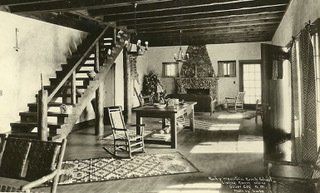 A black and white photo of a living room with stairs