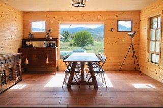 Woman with dark hair smiles at a restaurant, sitting on a ledge. Purple circle frame.