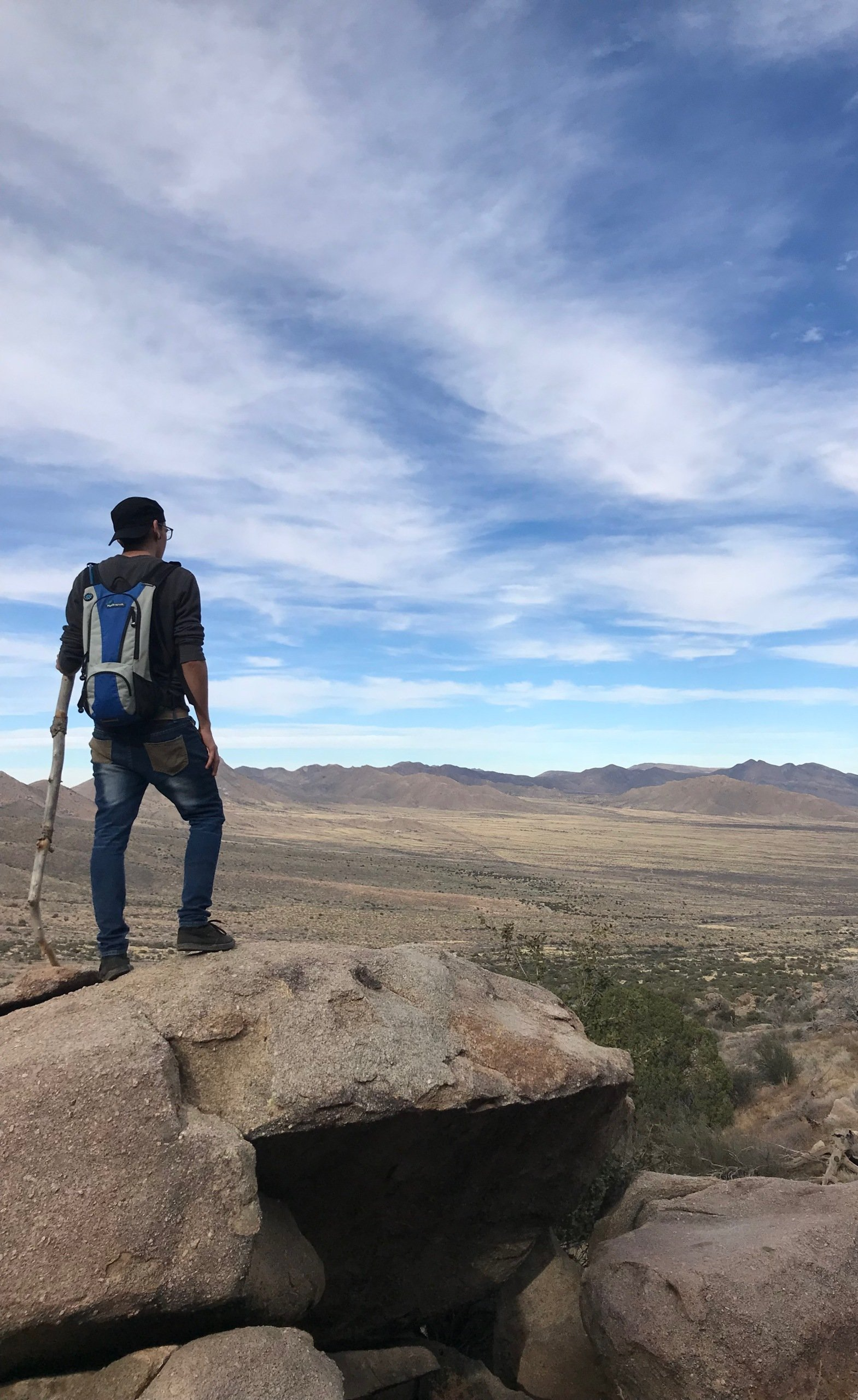 A man with a backpack is standing on top of a rocky hill.