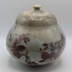 Ceramic jar with lid, pale green with maroon floral pattern.