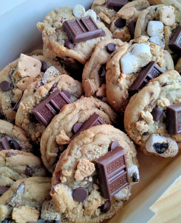 Close-up of a box filled with s'mores cookies, featuring Hershey's chocolate, marshmallows, and graham crackers.
