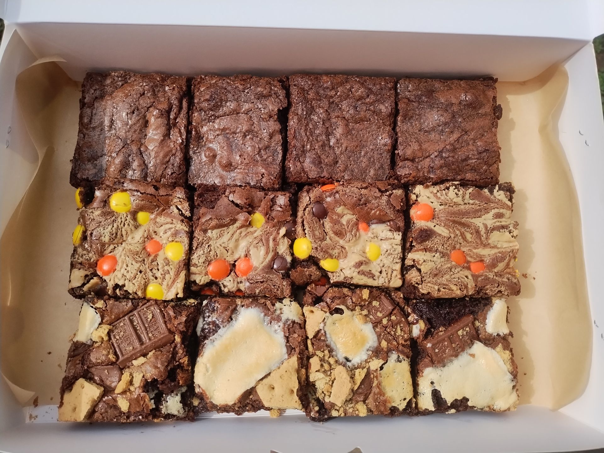 Box of brownies, some plain, some with candy toppings like Reese's Pieces and chocolate chunks.