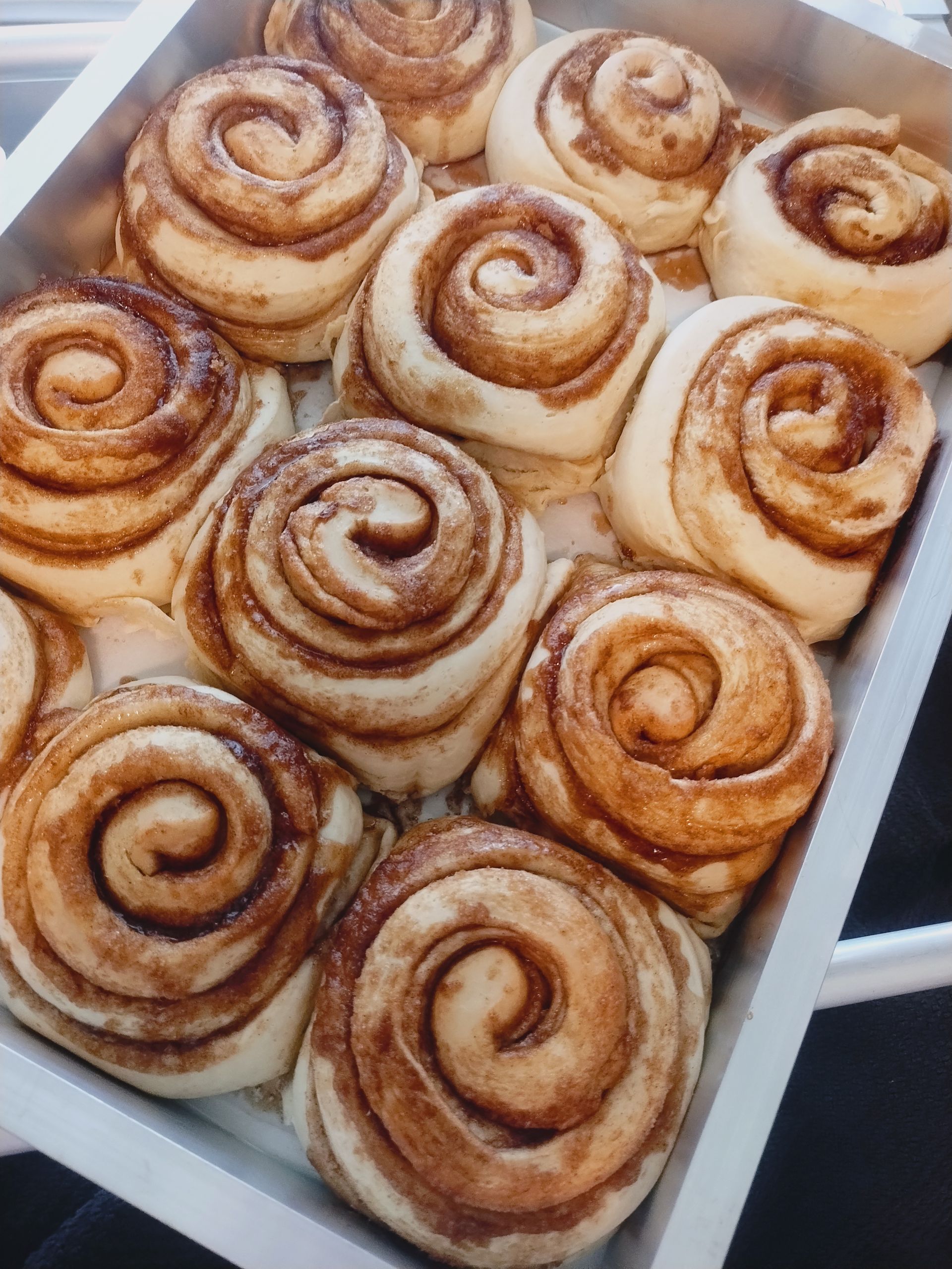 Cinnamon rolls in a metal baking pan, swirled with cinnamon sugar, light brown, baked.