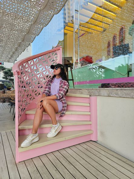 A woman is sitting on a set of pink stairs.