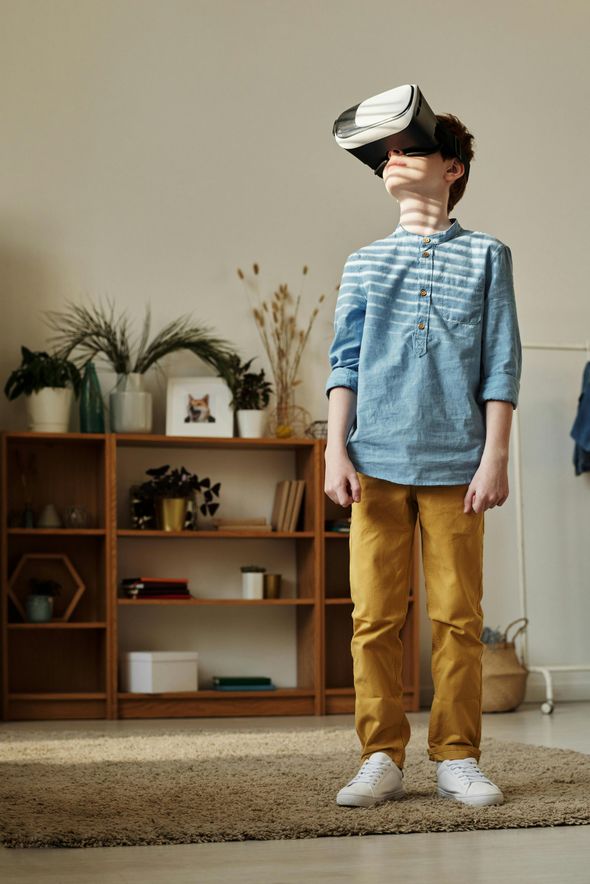 A young boy is wearing a virtual reality headset in a living room.