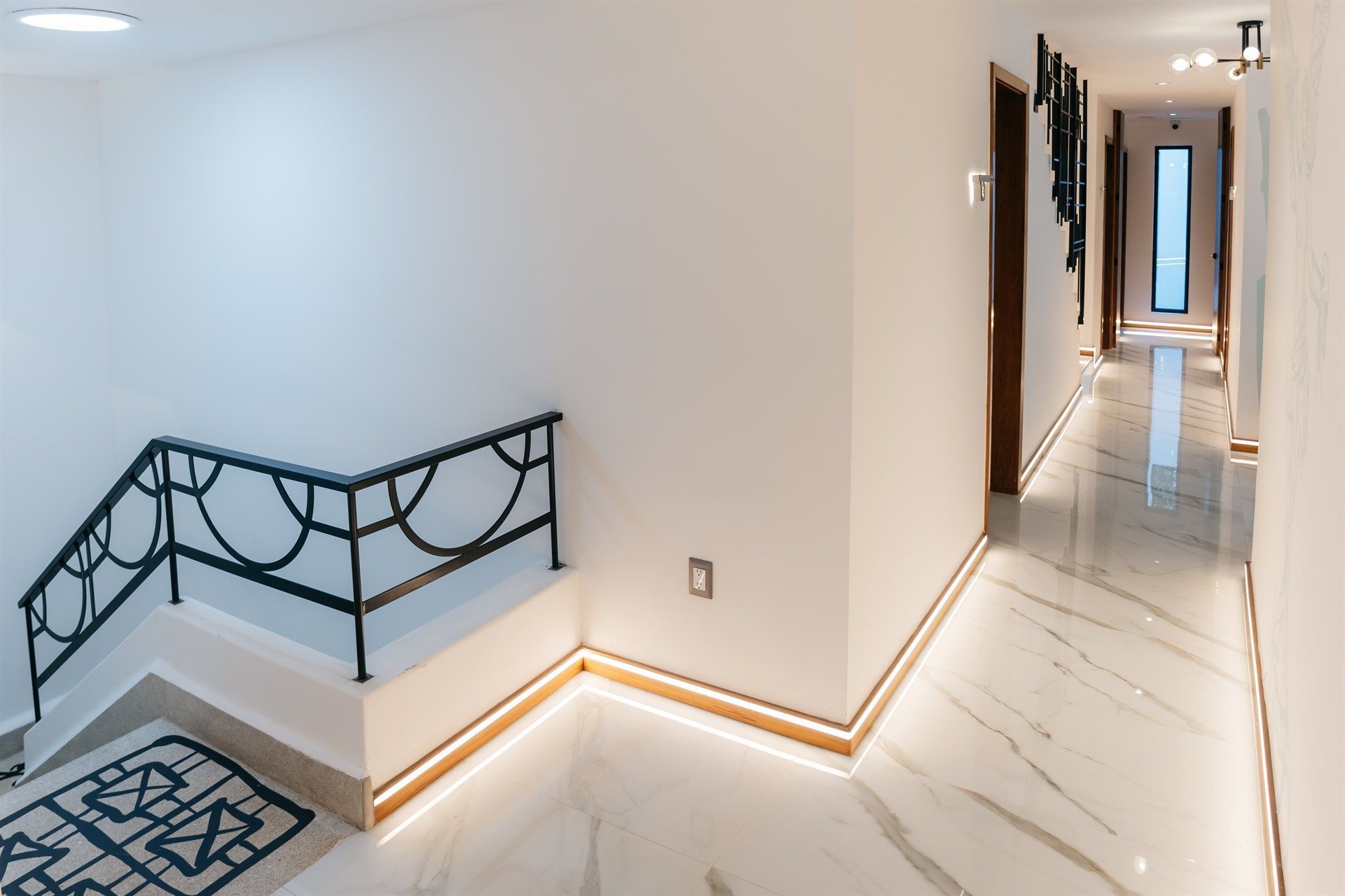 Un largo pasillo con escaleras y suelo de mármol.