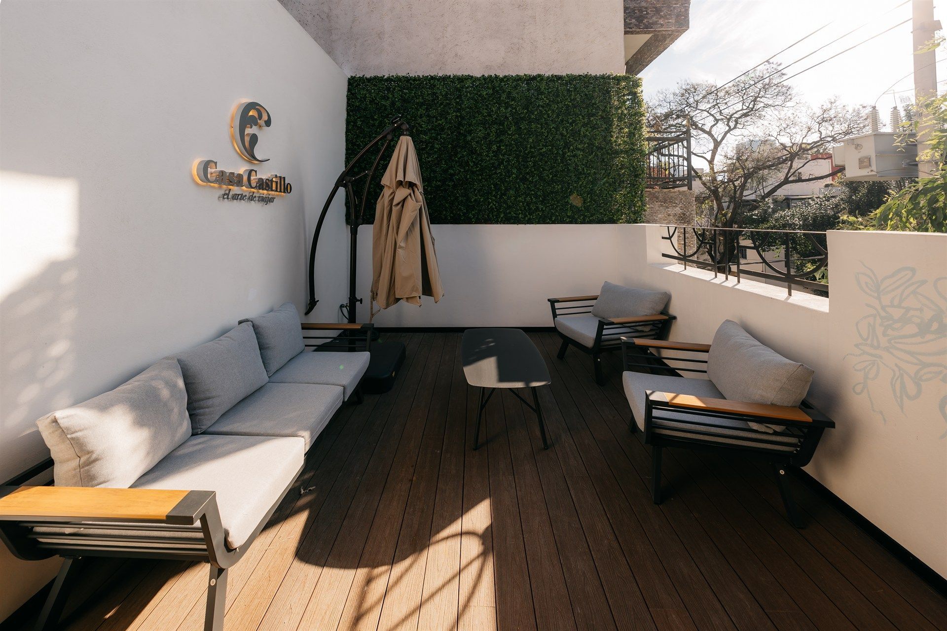 Un balcón con sofá, sillas y sombrilla.