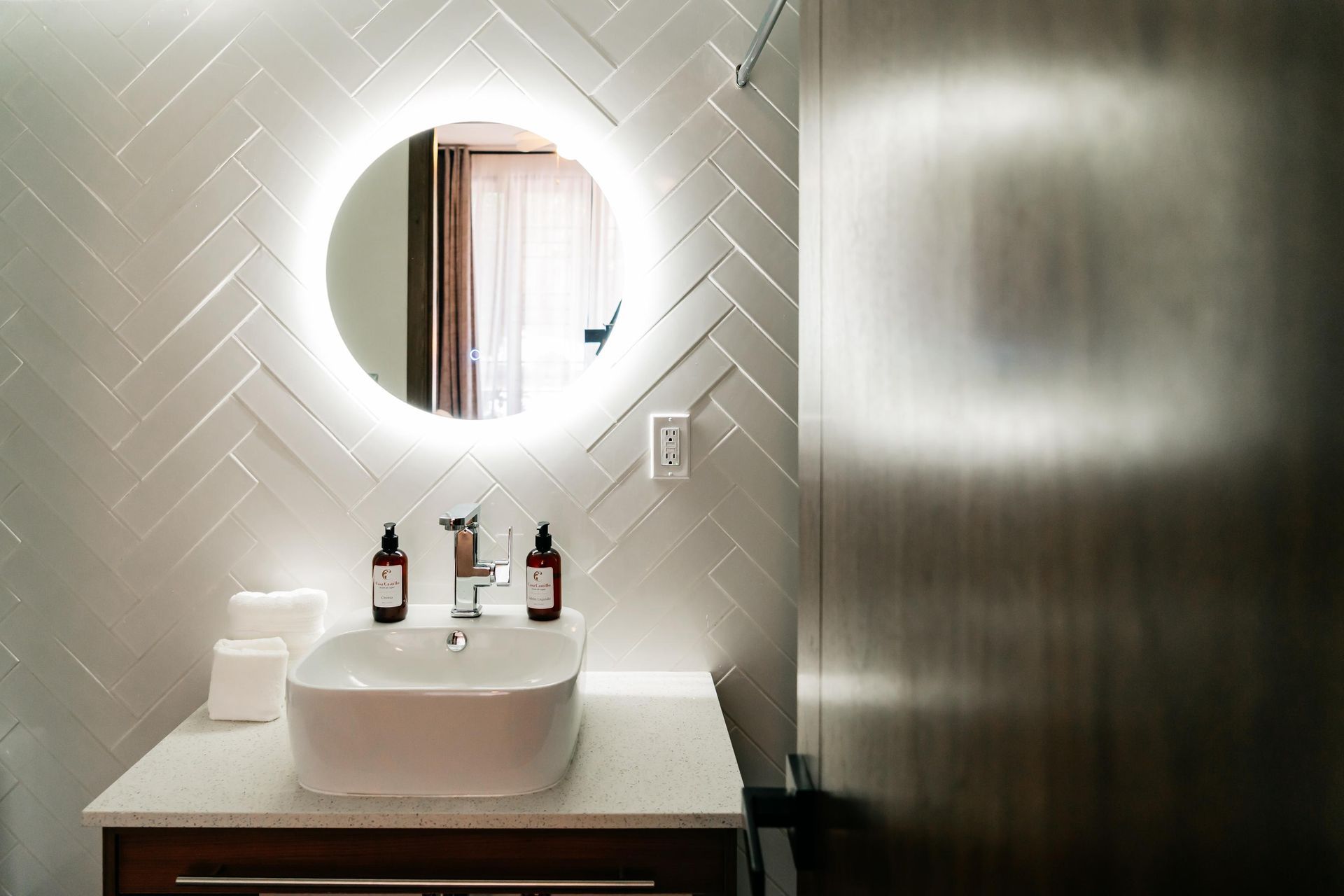 Un baño con lavabo y espejo redondo.