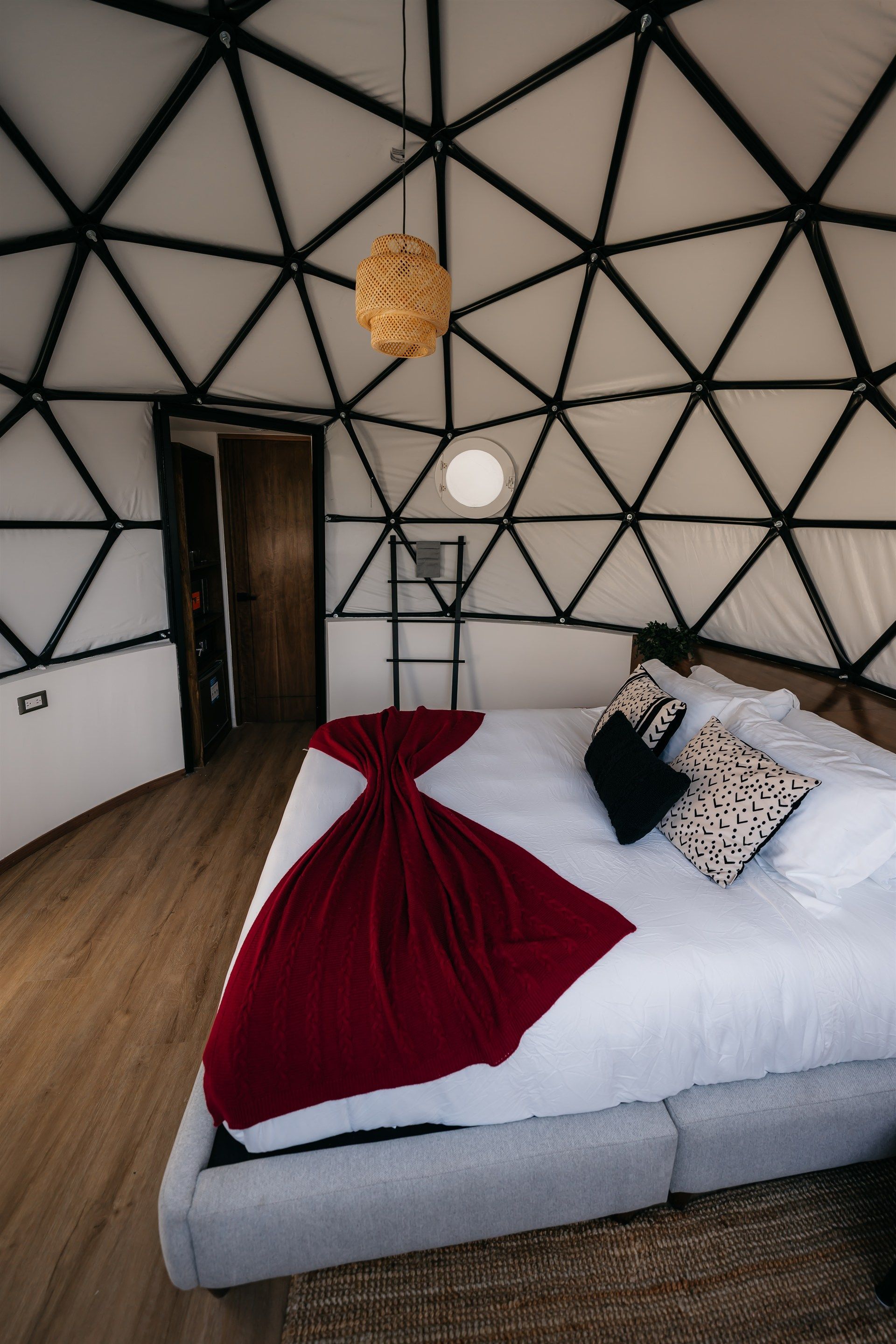 Un dormitorio con una cama y una manta roja en una cúpula.