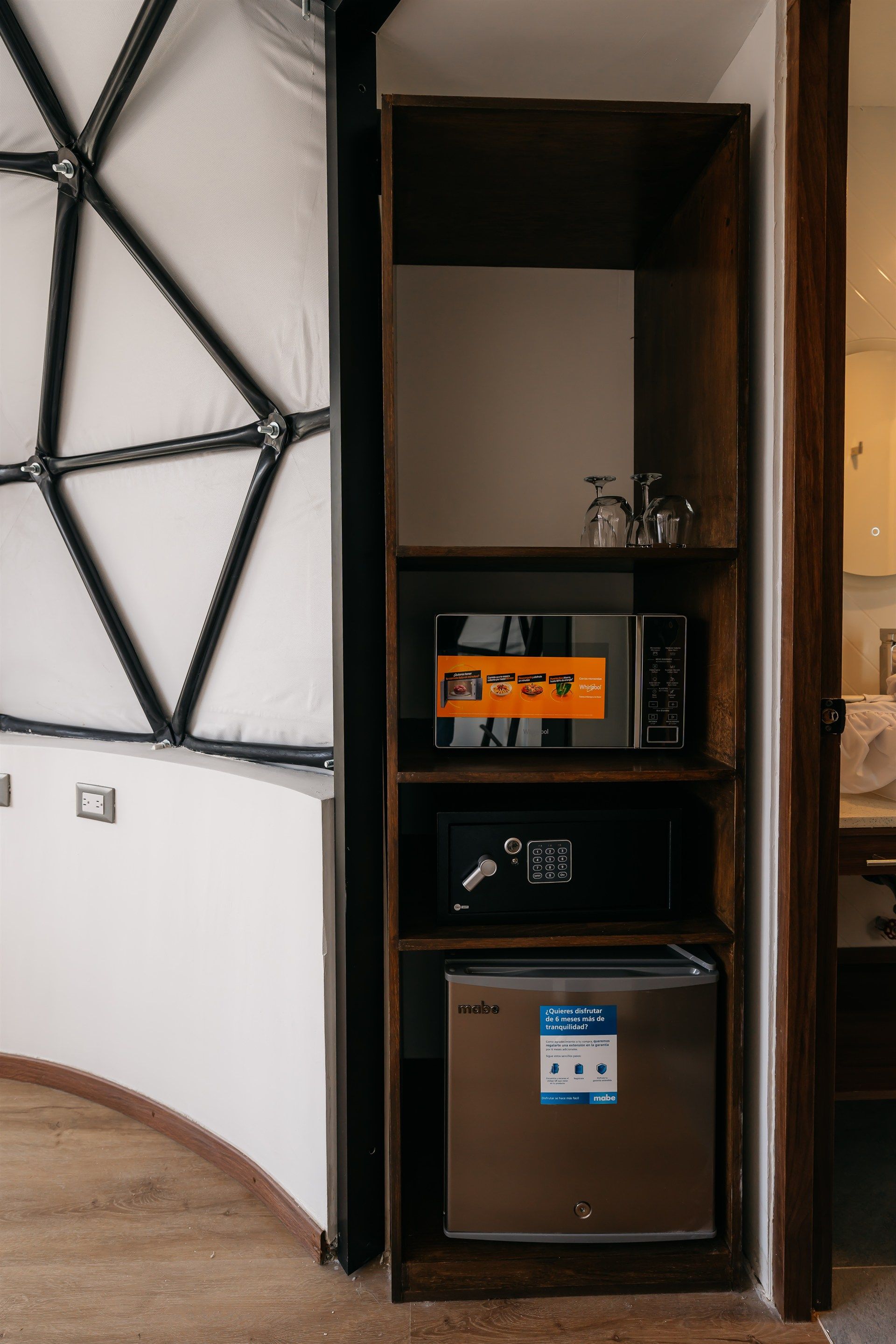 Un estante con un microondas y una mini nevera en una habitación.