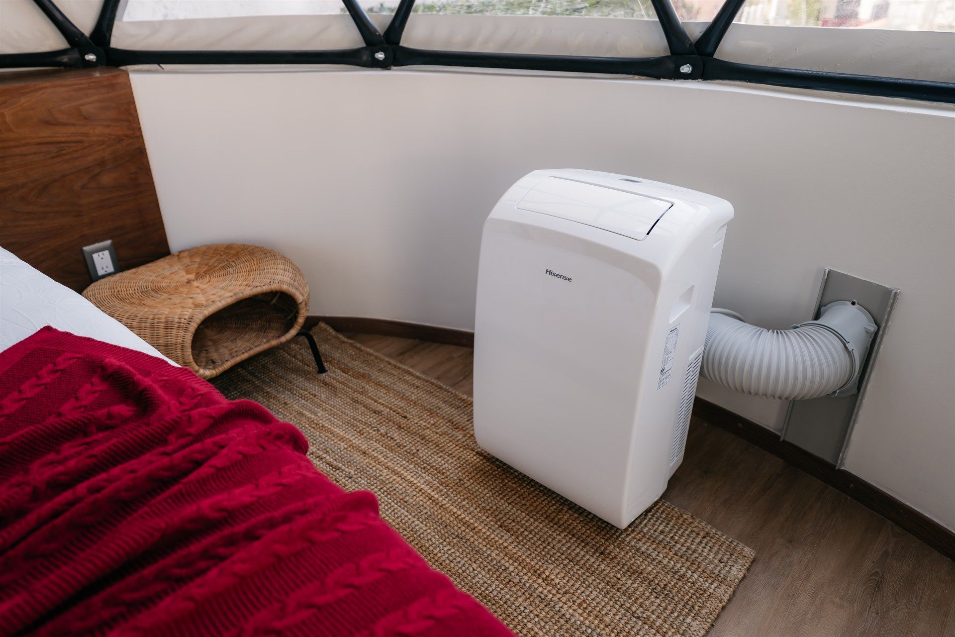 Un acondicionador de aire portátil está junto a una cama en un dormitorio.