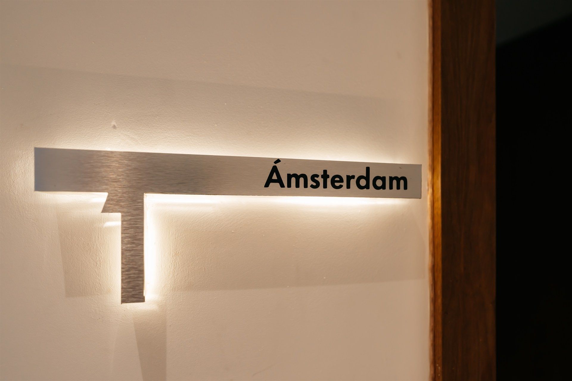 Un cartel en una pared que dice Amsterdam con una luz detrás.