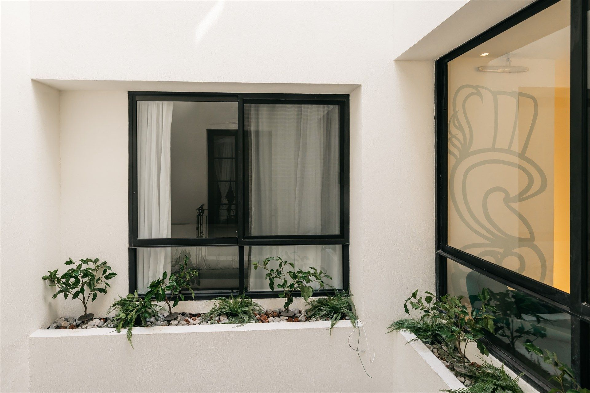 Una pared blanca con una ventana y una jardinera con plantas.