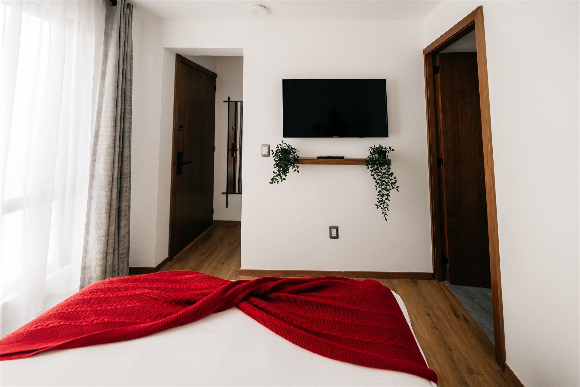 Un dormitorio con una cama y un televisor en la pared.