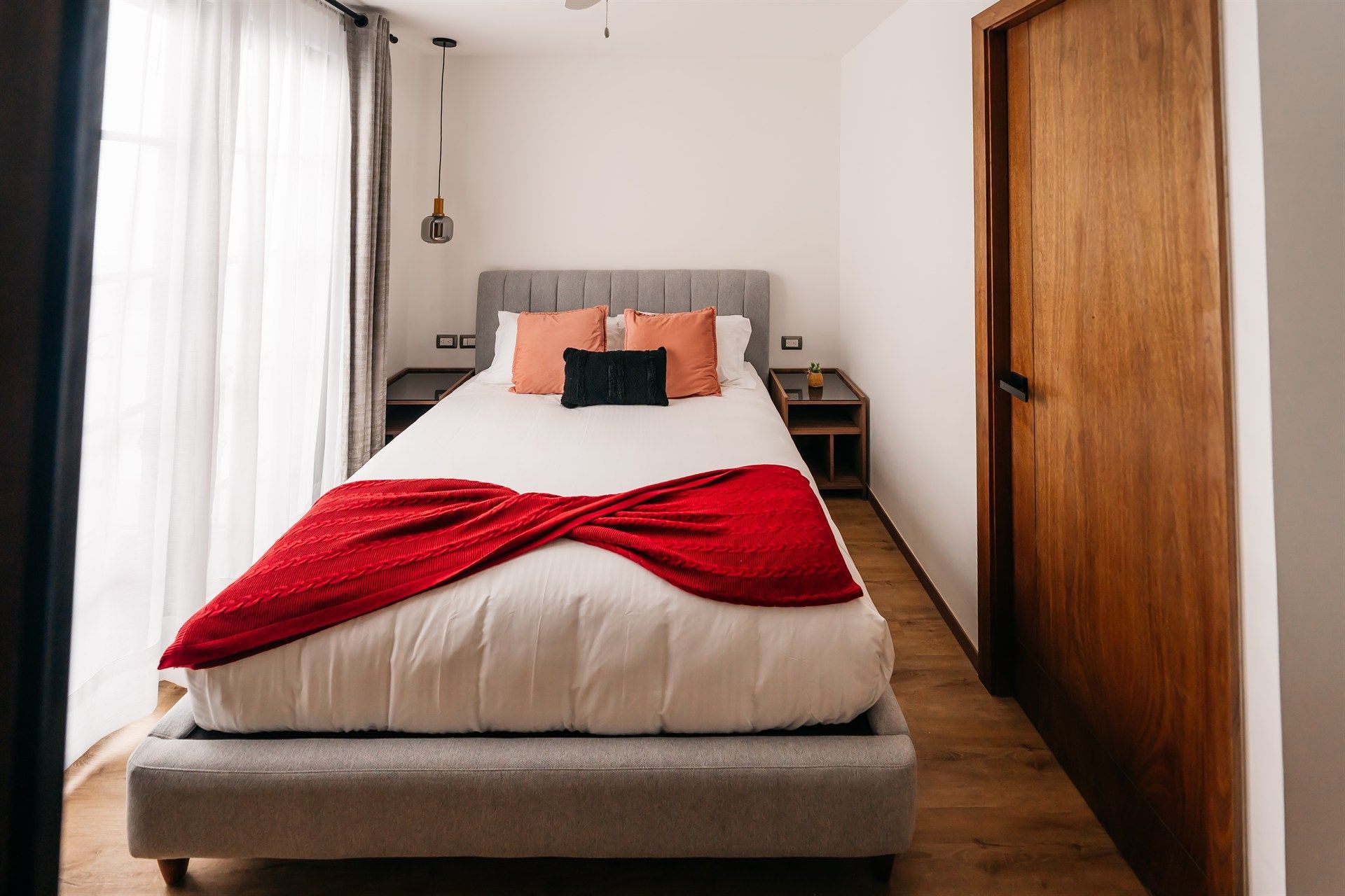 Un dormitorio con una cama y una manta roja encima.
