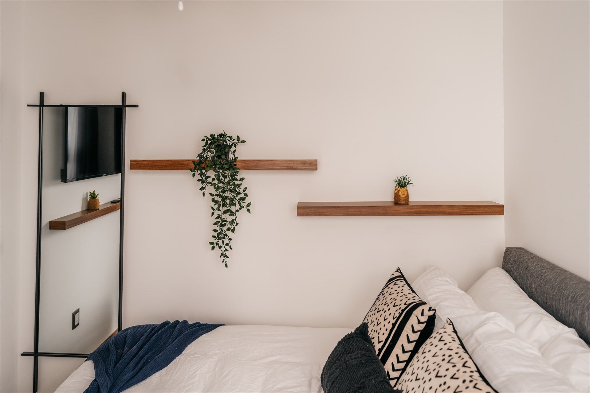 Un dormitorio con una cama, estanterías, un televisor y un espejo.