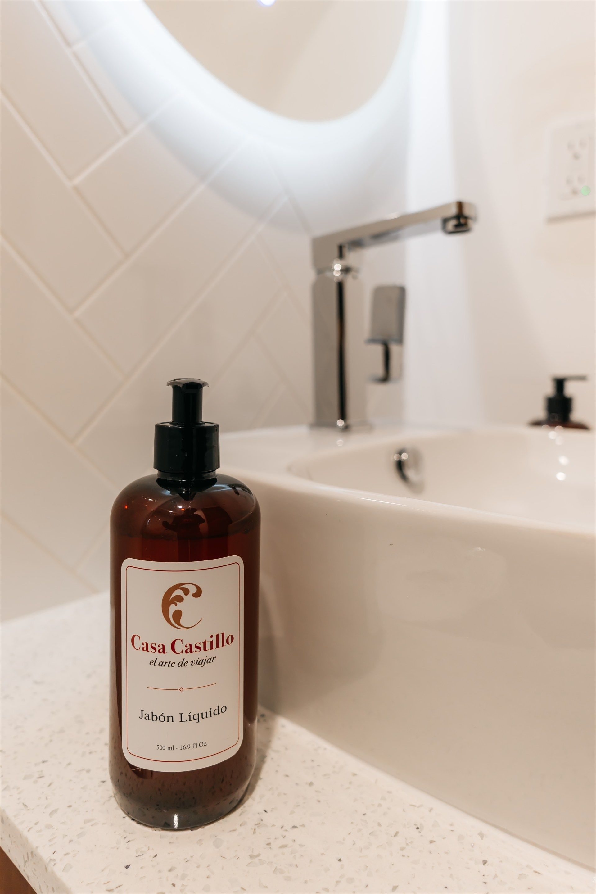 Una botella de loción está sobre el mostrador del baño, al lado de un lavabo.
