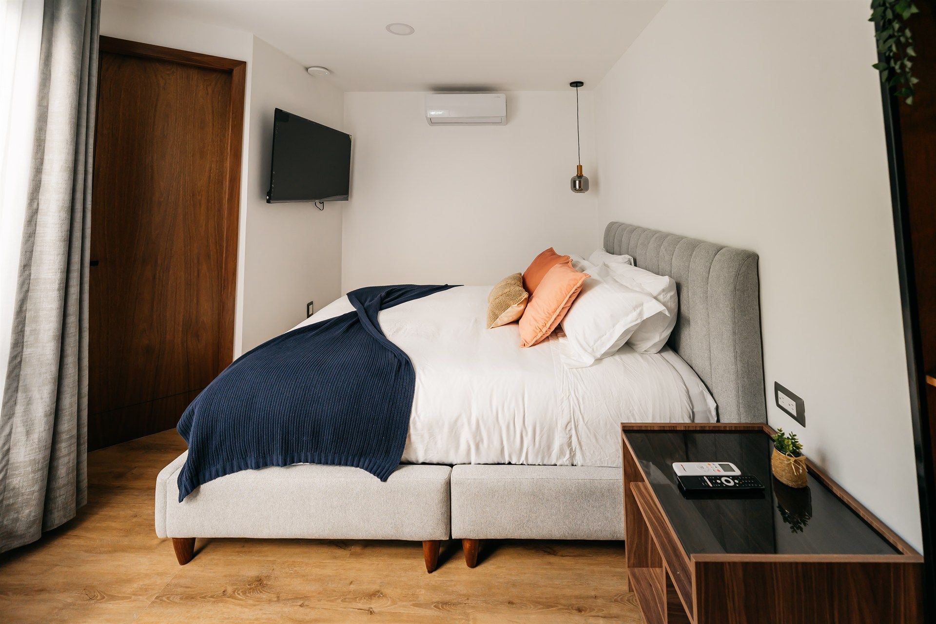 Un dormitorio con una cama grande y un televisor en la pared.