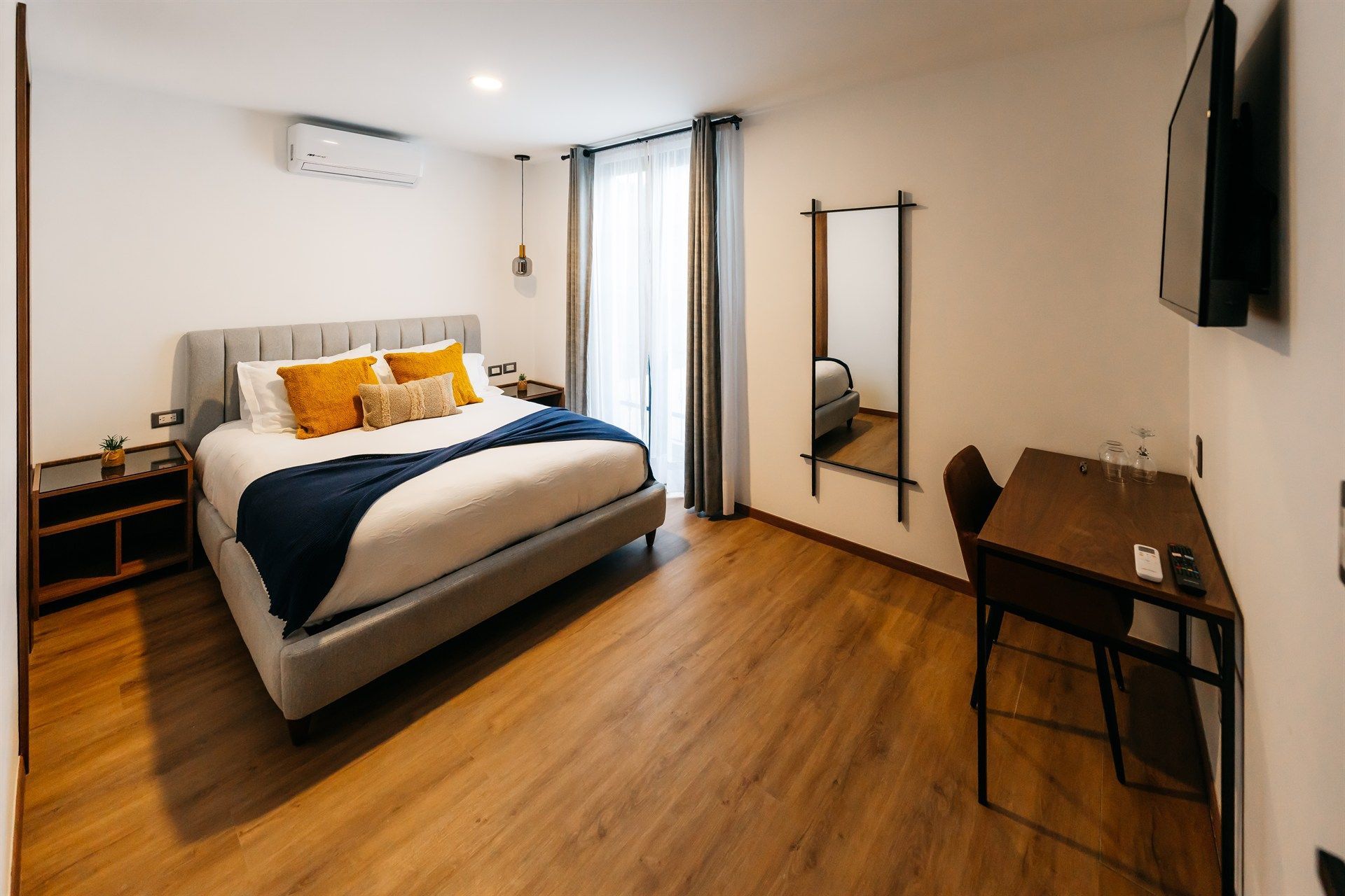 Una habitación de hotel con una cama grande, escritorio y televisión.