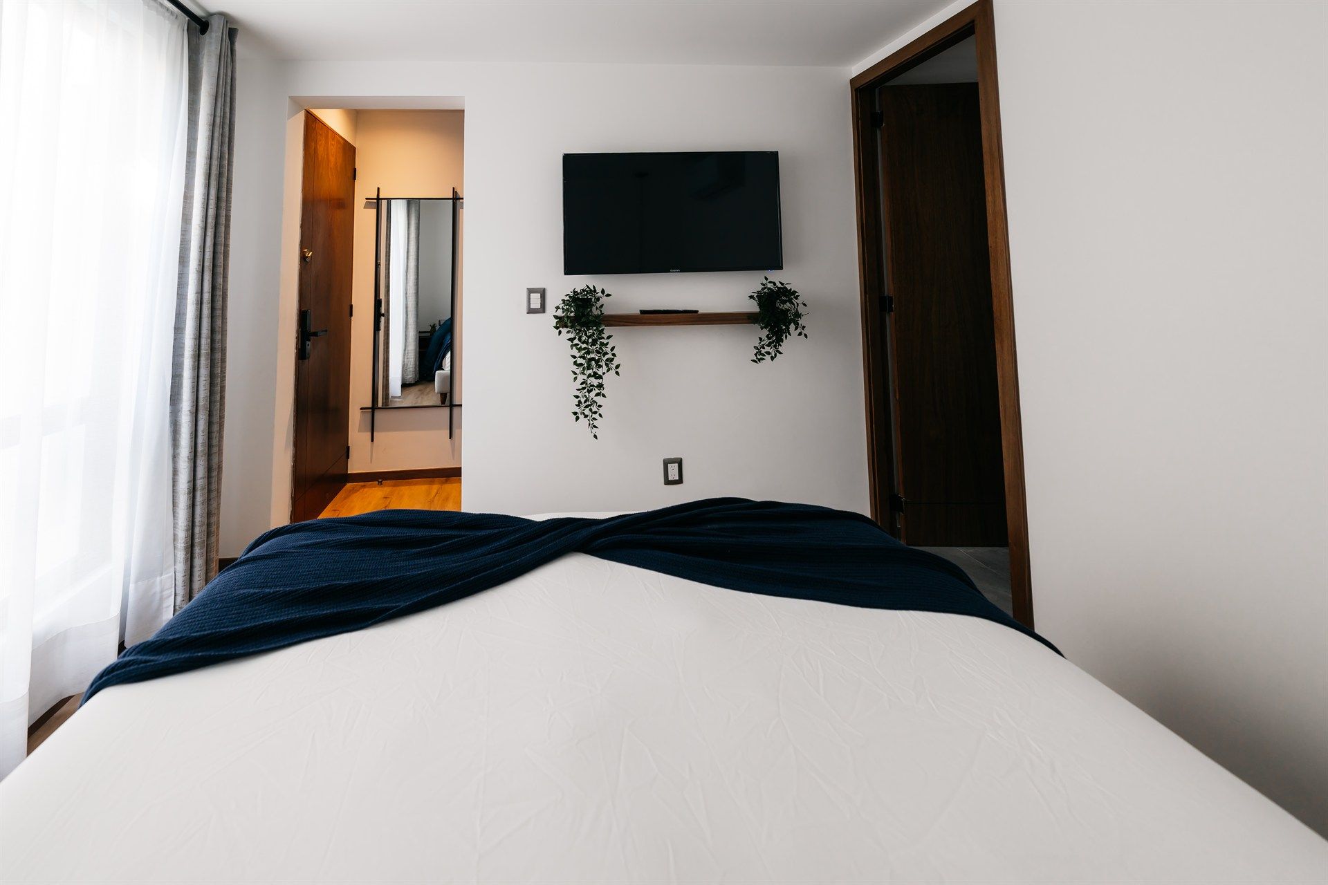 Un dormitorio con cama, televisión y espejo.