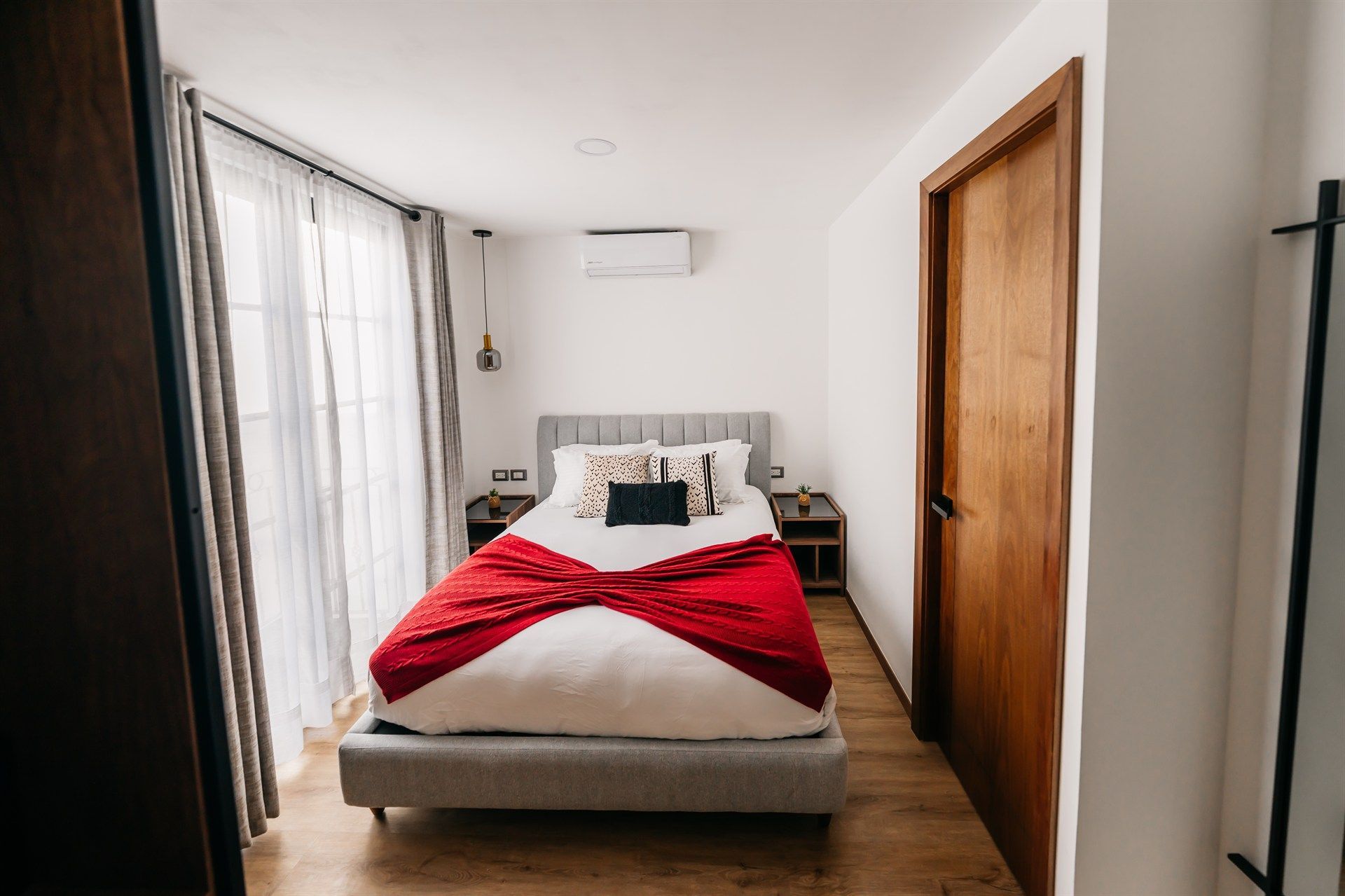 Un dormitorio con una cama y una manta roja encima.