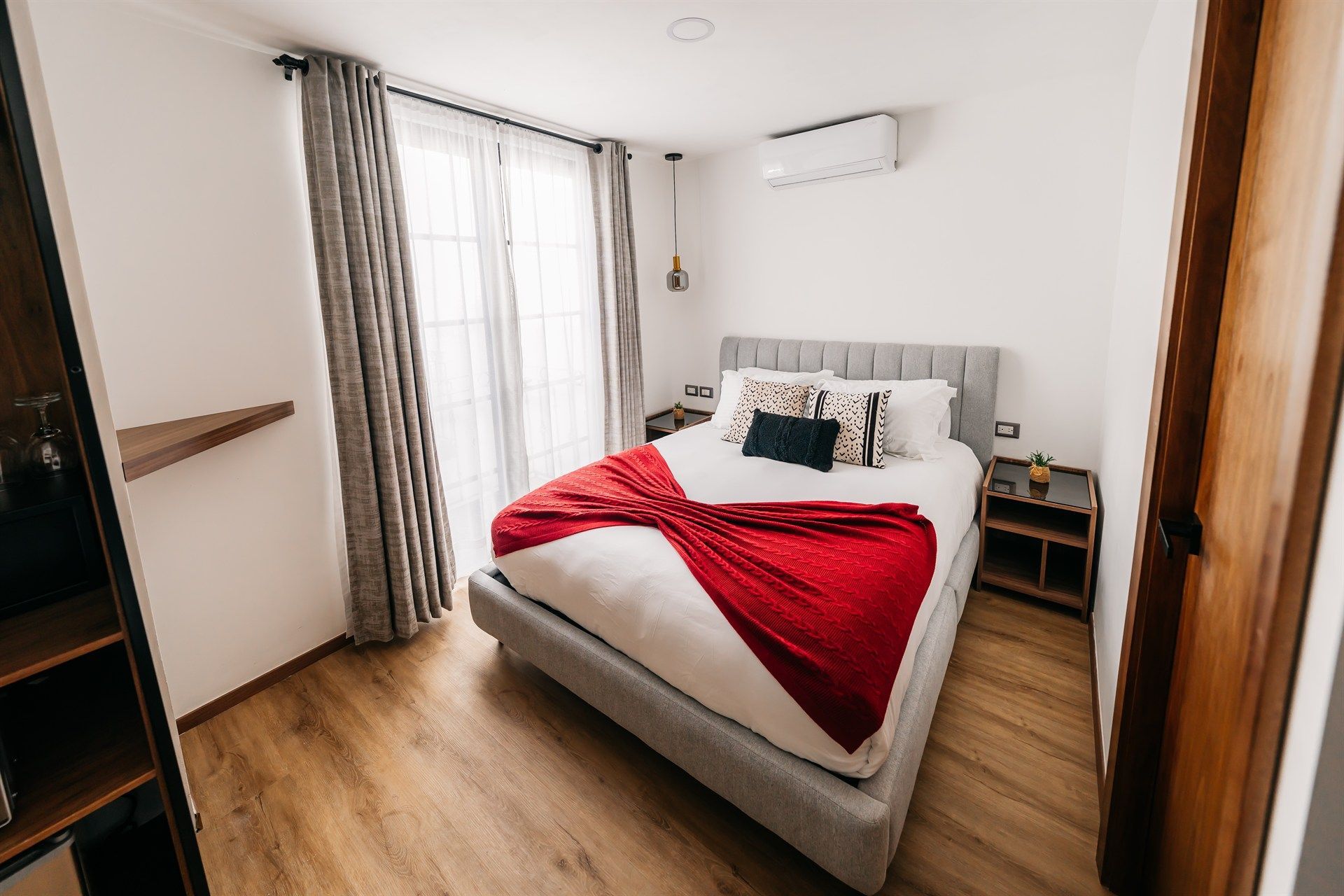 Un dormitorio con una cama grande y una manta roja encima.