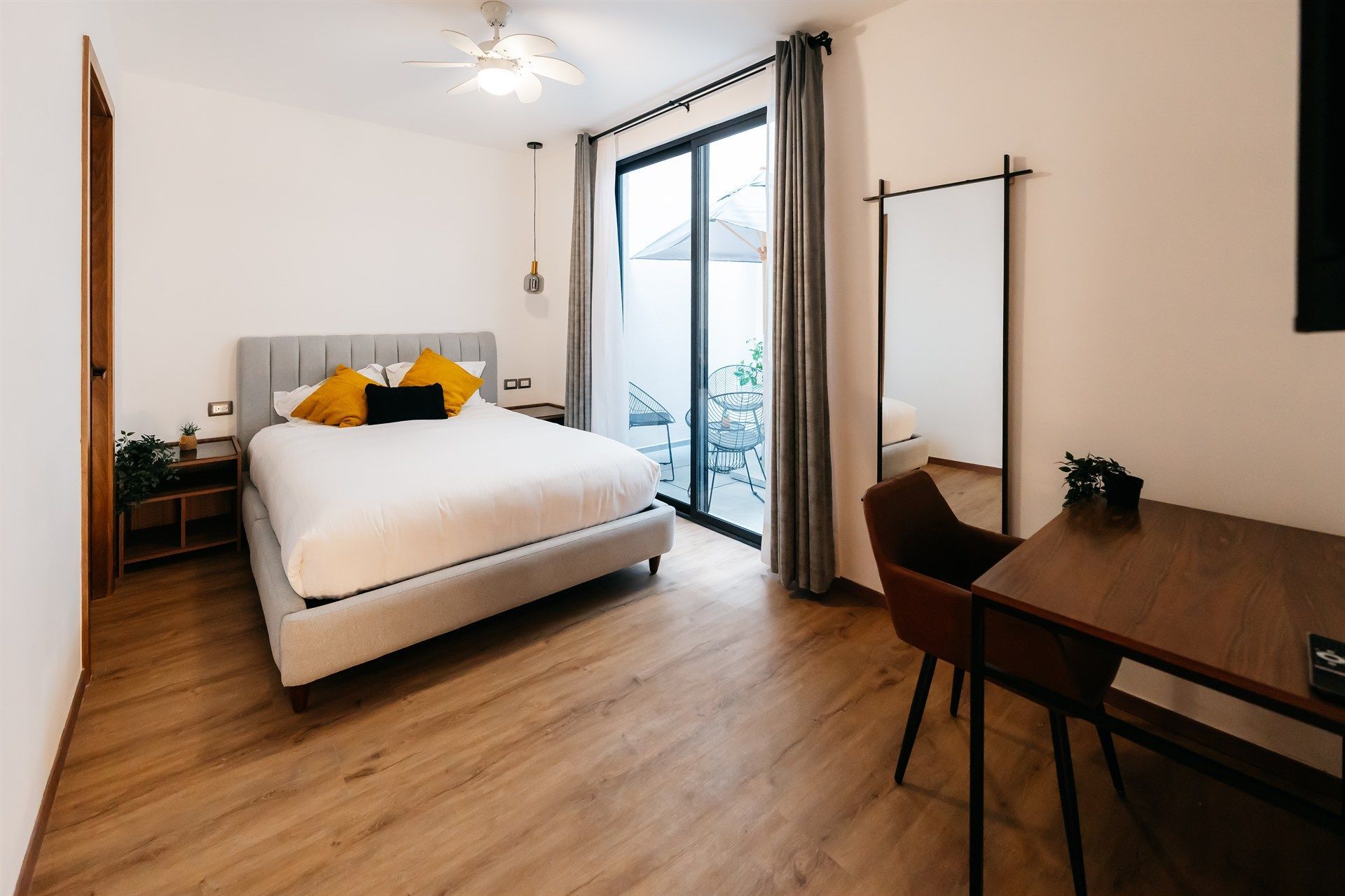 Un dormitorio con una cama grande, escritorio, silla y espejo.