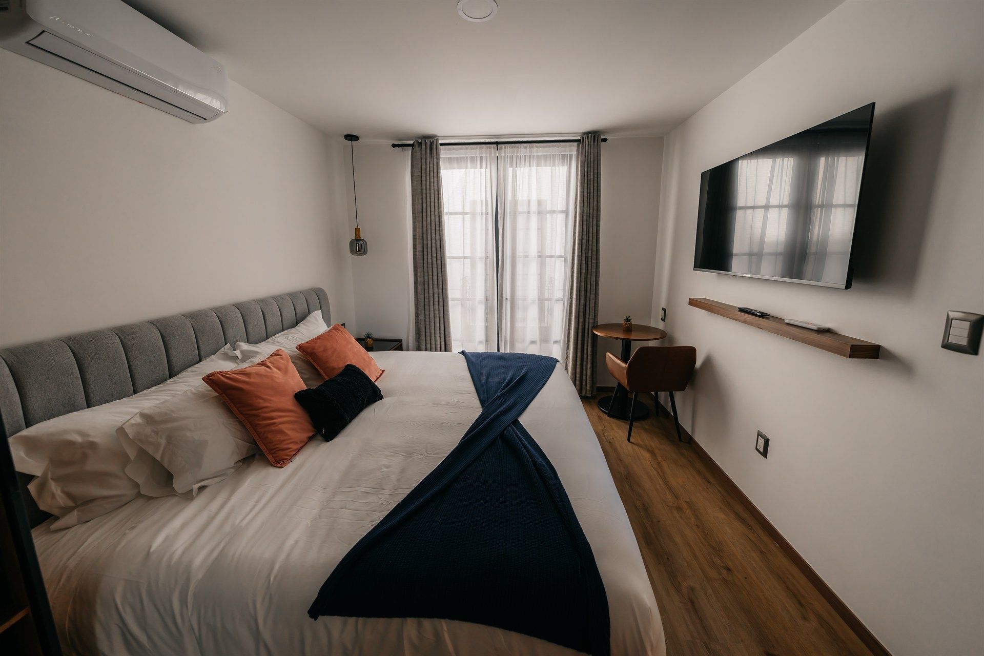 Un dormitorio con una cama grande y un televisor de pantalla plana en la pared.