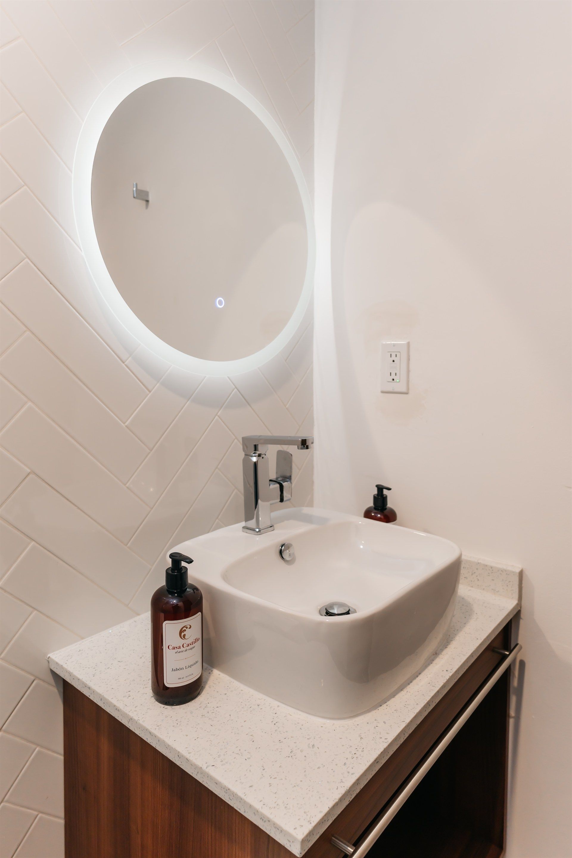 Un baño con lavabo, espejo y dispensador de jabón.