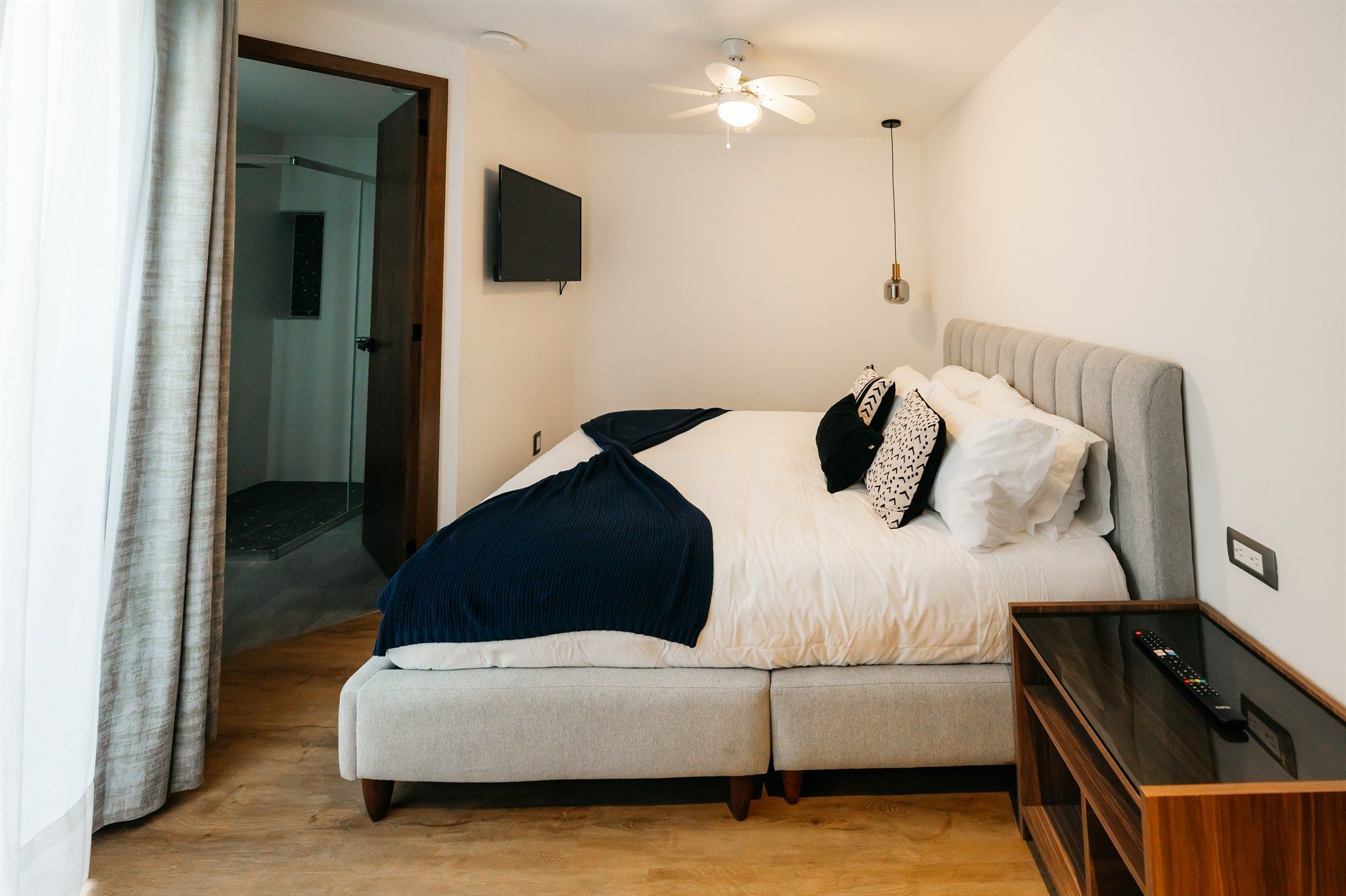 Un dormitorio con una cama grande y un televisor en la pared.