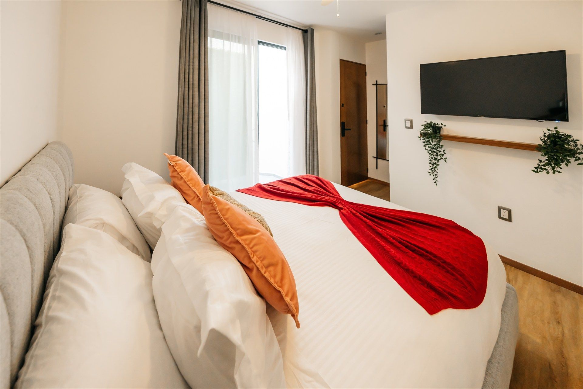 Un dormitorio con una cama grande y un televisor de pantalla plana en la pared.