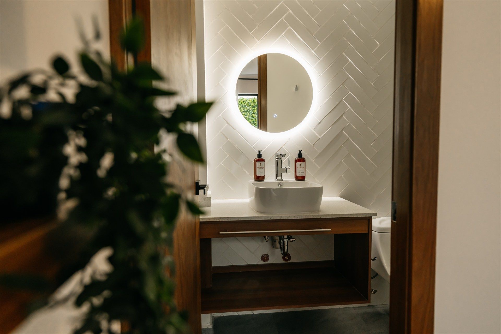 Un baño con lavabo y espejo redondo.