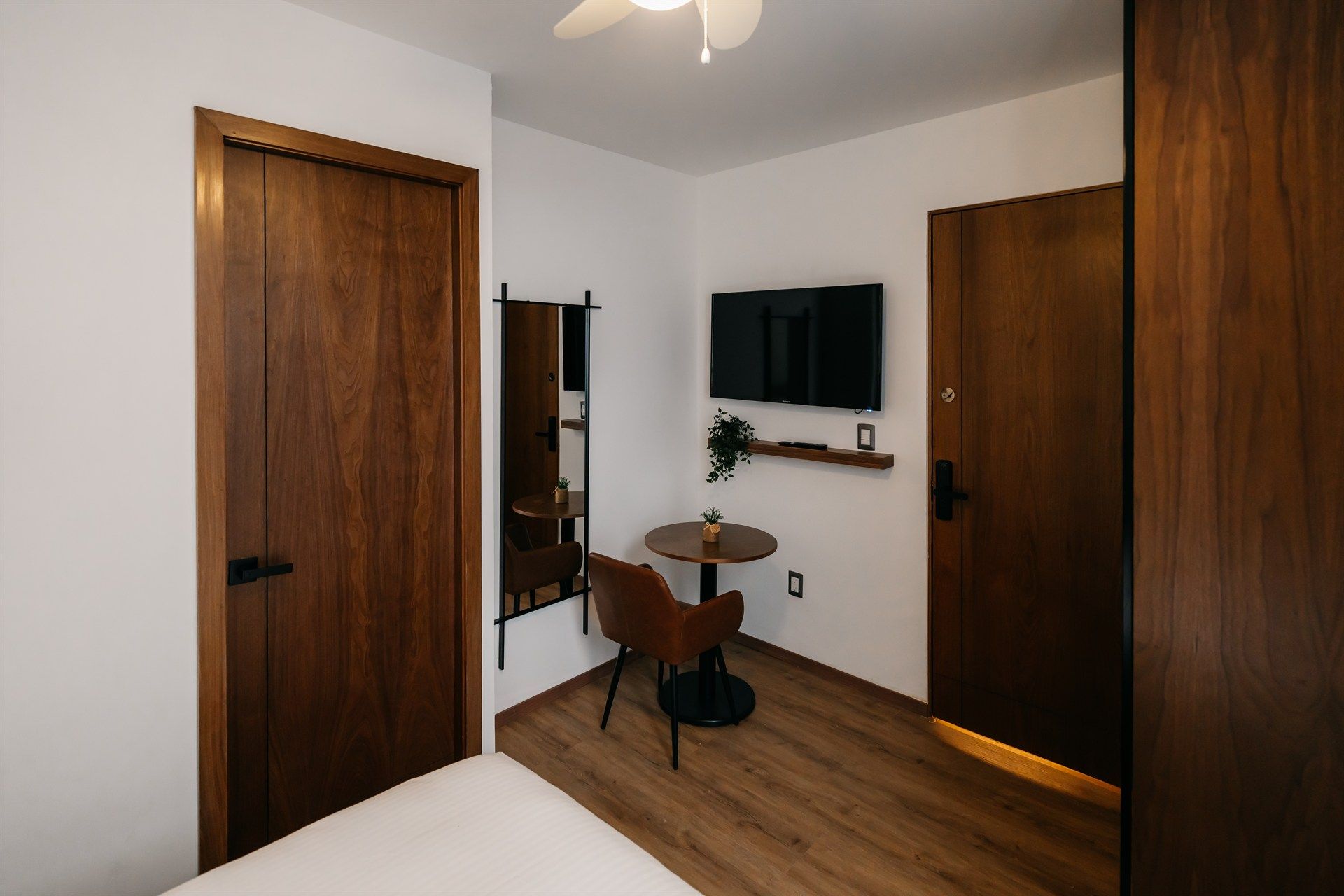 Una habitación de hotel con una mesa, una silla, un televisor y un espejo.