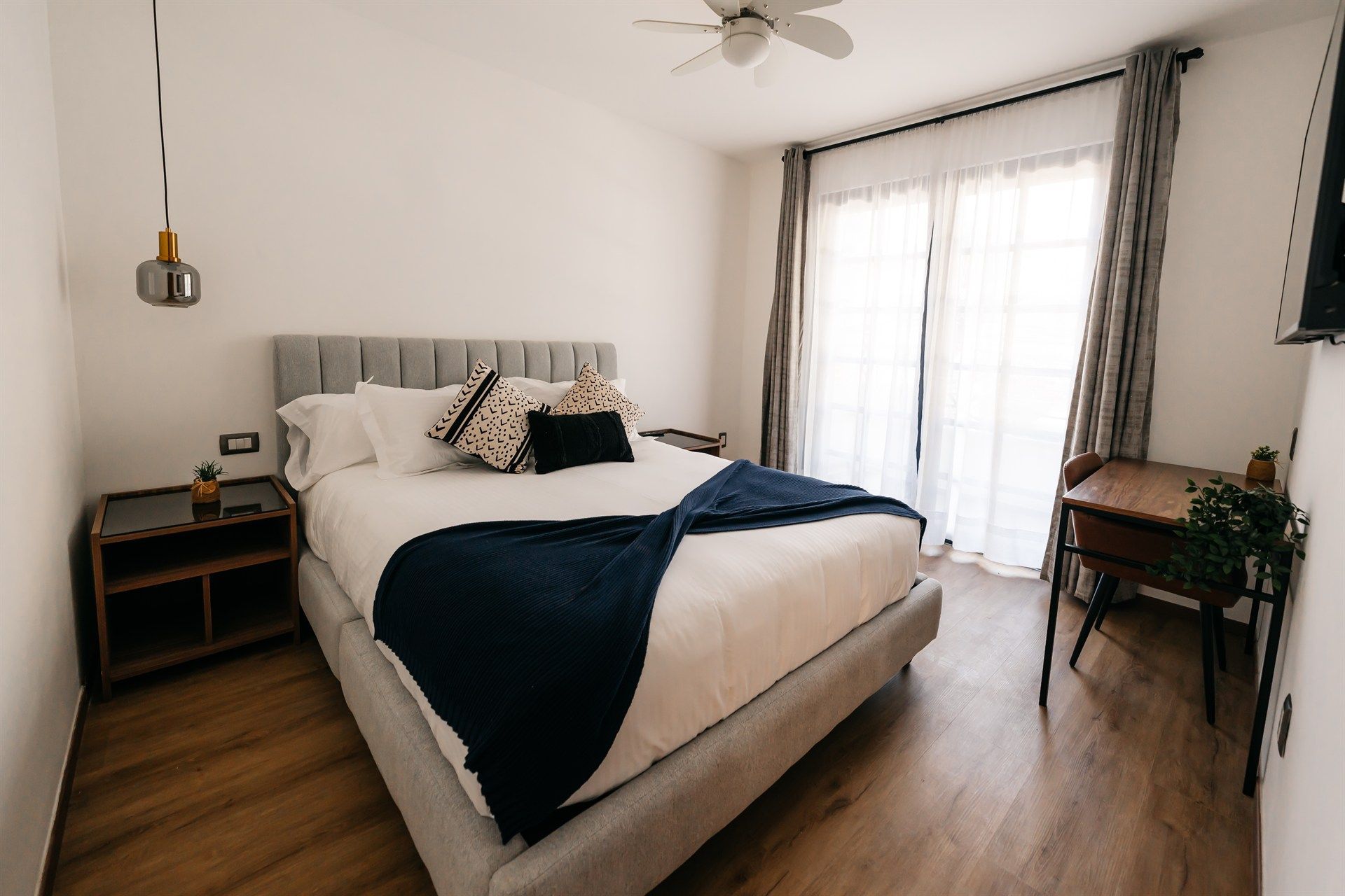 Un dormitorio con una cama grande, un escritorio y un ventilador de techo.