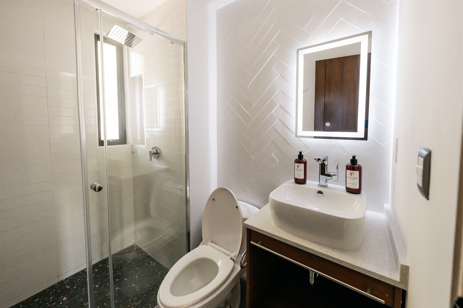 Un baño con inodoro, lavabo, ducha y espejo.