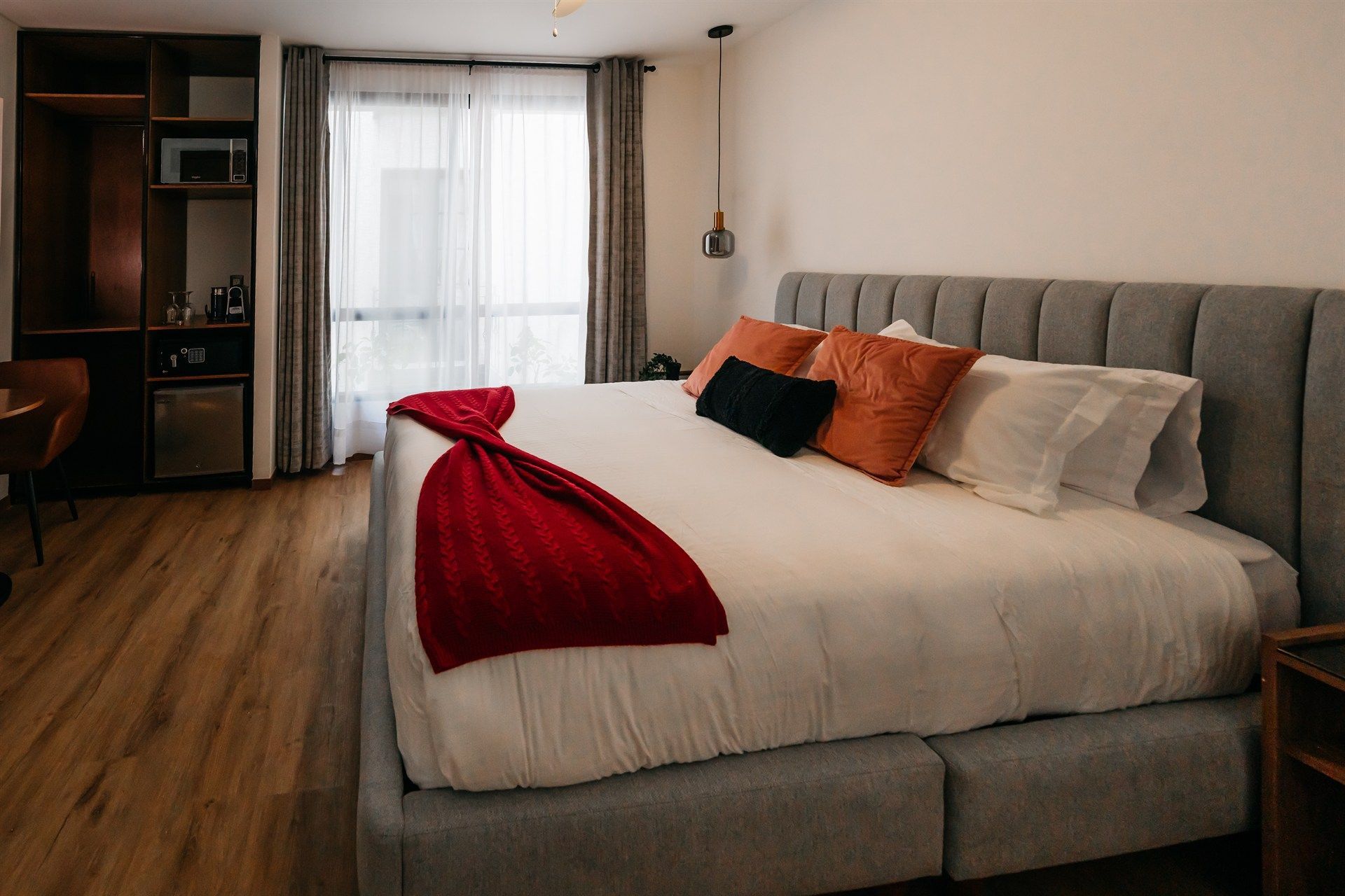 Una cama grande con una manta roja encima en una habitación de hotel.