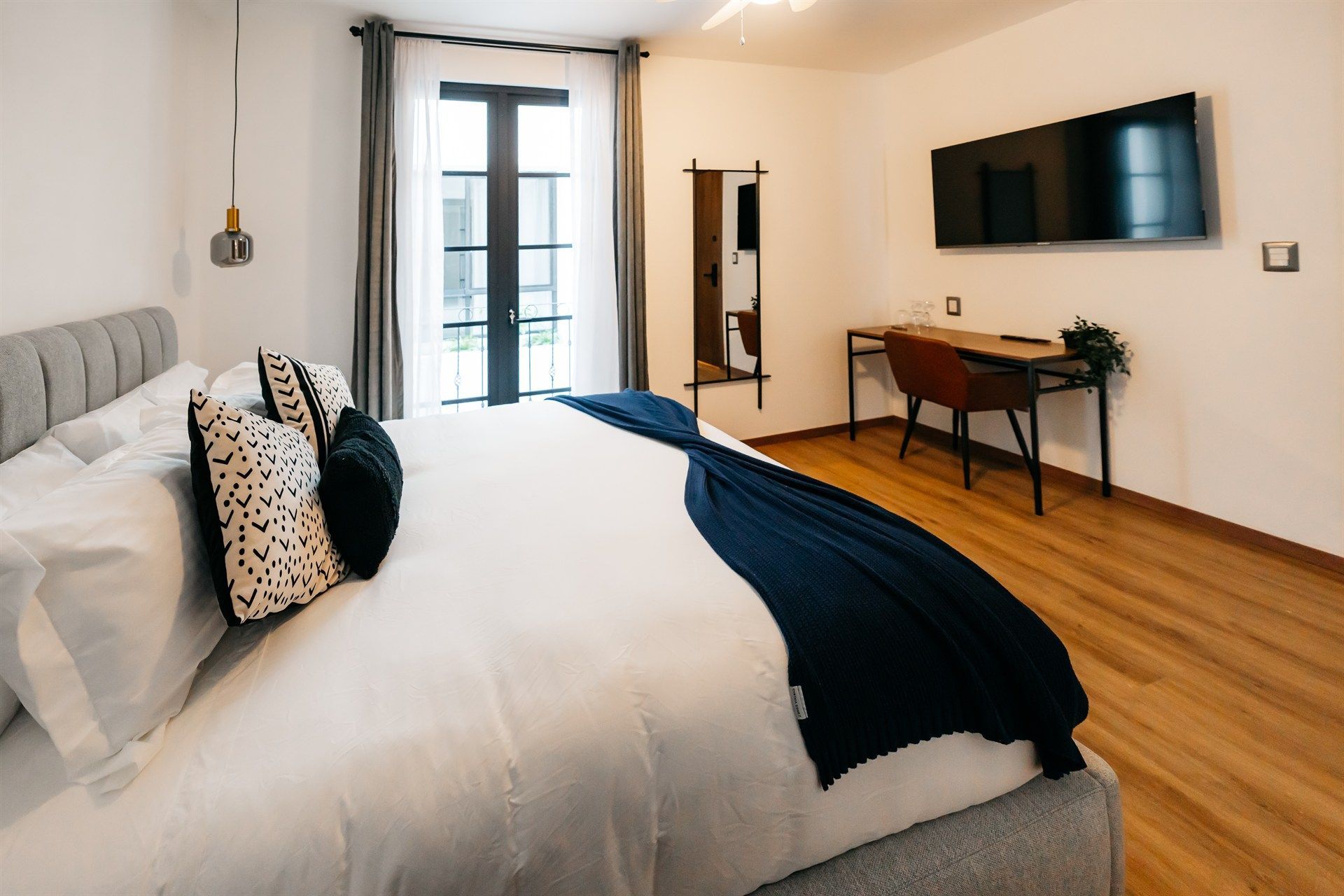 Un dormitorio con una cama king size, escritorio y televisión.