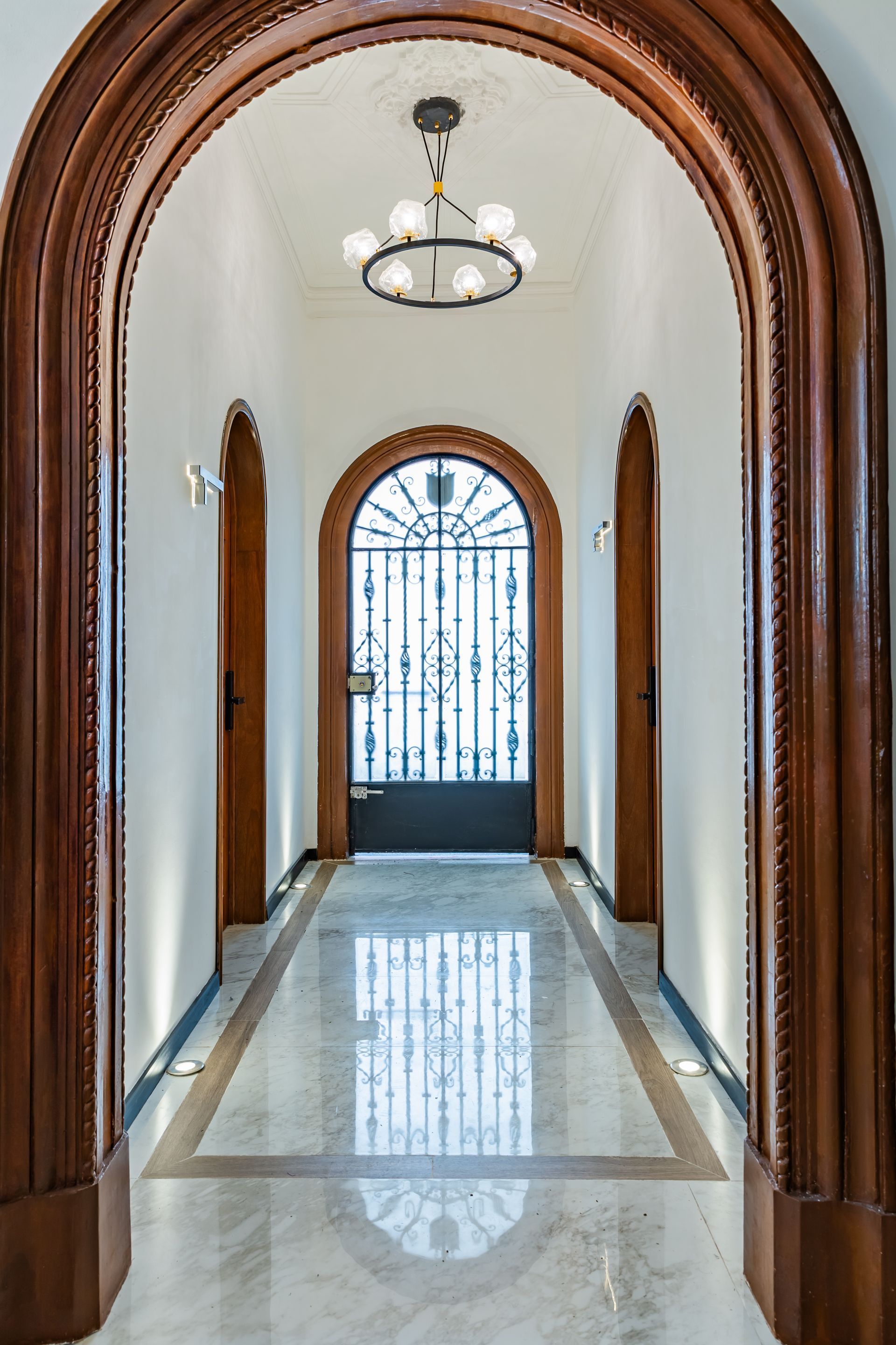 A hallway with arched doors and a chandelier hanging from the ceiling.