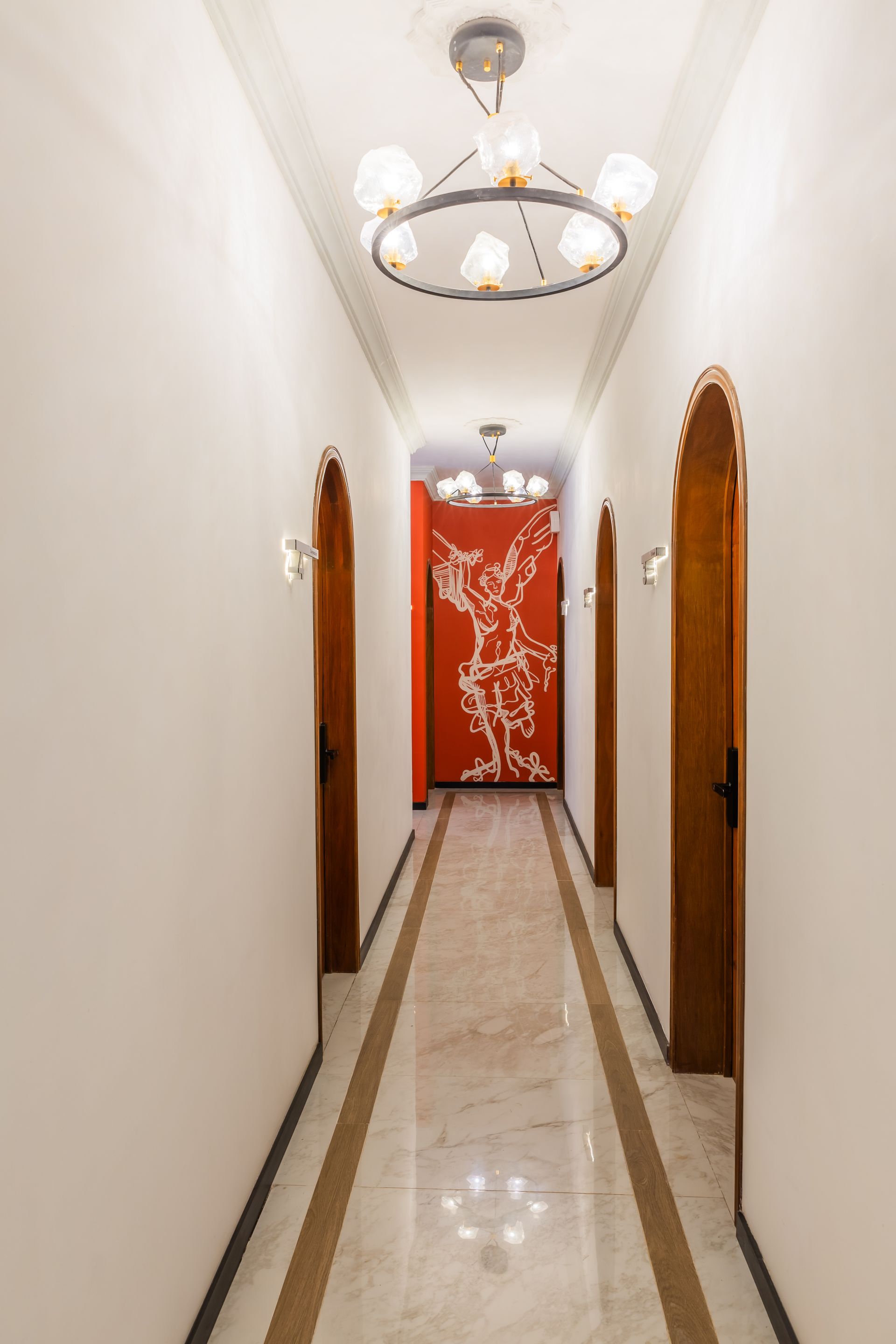 Un largo pasillo con un cuadro en la pared y una lámpara de araña colgando del techo.