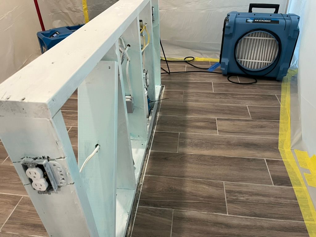 White, open wall studs with electrical outlets, a dehumidifier, and tile flooring.