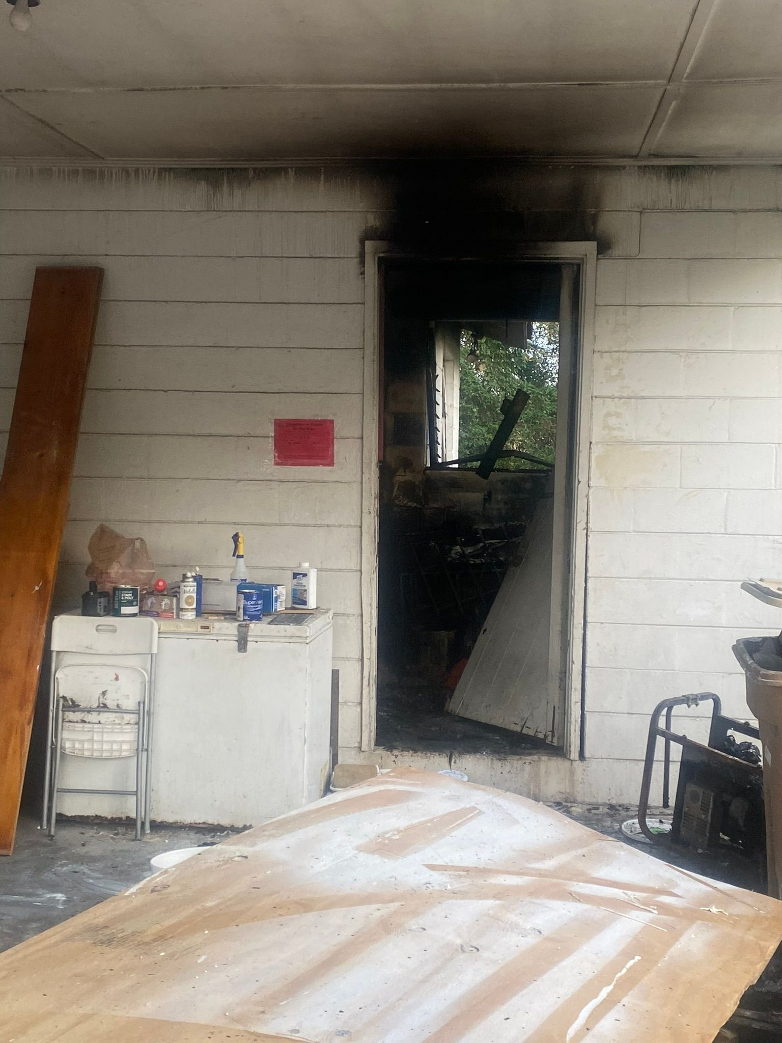 A white building with a door that is open and a wooden table.