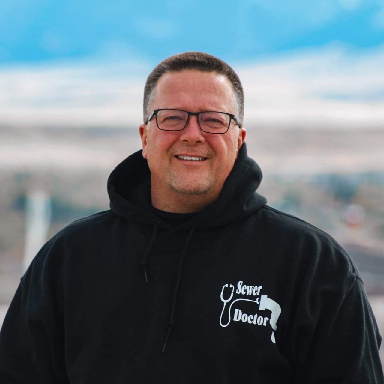 A man wearing a black hoodie that says sewer doctor
